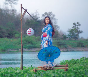 Portrait of woman with umbrella standing by plants