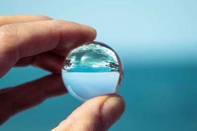 Close-up of hand holding glass against blue background