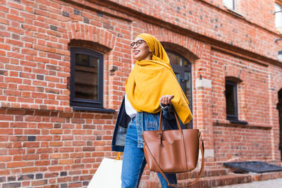 Portrait of young woman standing against wall