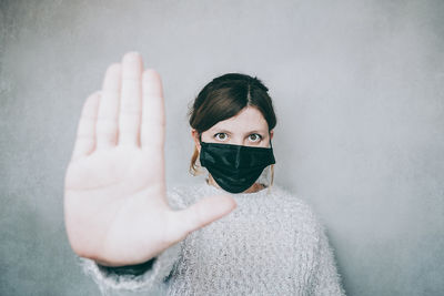 Portrait of young woman standing against wall