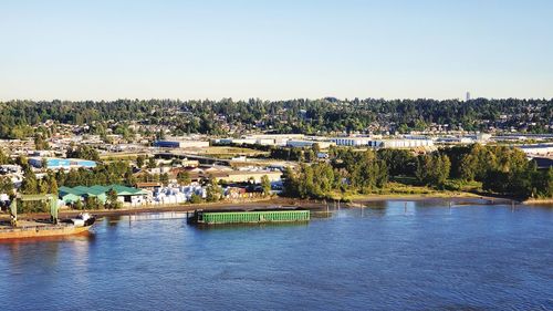 Scenic view of river by buildings against clear sky