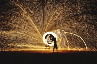 Silhouette person spinning wire wool at night