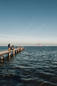 People on pier over sea against sky