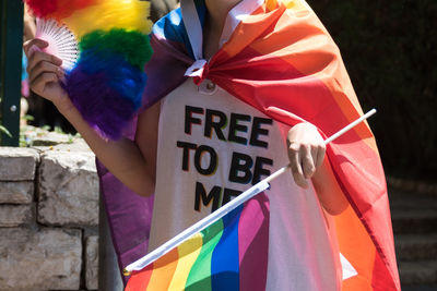 Midsection of lesbian with rainbow flag in city