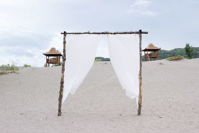 Clothes drying on beach by building against sky