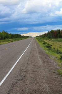 The long view of a highway with a storm brewing in the distance.