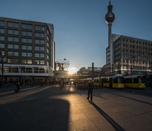 Low angle view of fernsehturm tower amidst buildings against sky during sunset