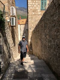 Man standing in alley against buildings