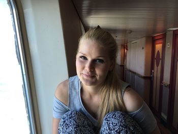 Portrait of smiling young woman sitting by window