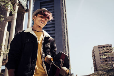 Happy young man standing against building in city