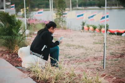 Woman using mobile phone while sitting on land