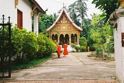 Rear view of people walking outside temple against building