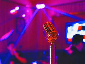 Close-up of microphone in illuminated nightclub