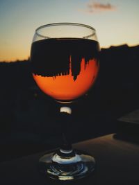 Close-up of wineglass against orange sky