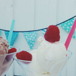 Close-up of ice cream with raspberries served in cups