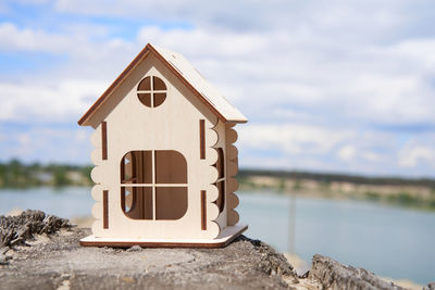 Close-up of small house on rock by lake against sky