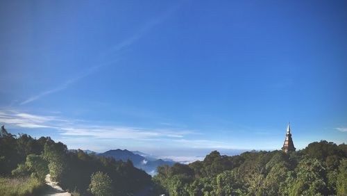 Panoramic view of trees and buildings against blue sky