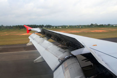 Airplane flying over airport runway against sky