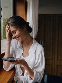 Young woman using mobile phone at home