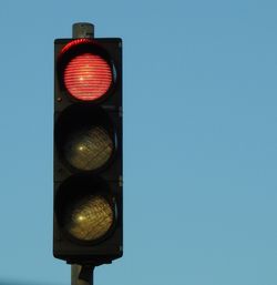 Low angle view of road sign against clear blue sky