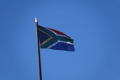 Low angle view of flag against clear blue sky