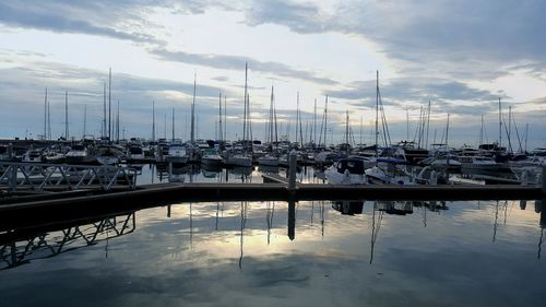 Sailboats moored at harbor against sky