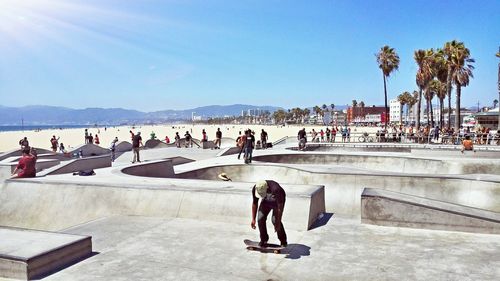 People enjoying summer at skateboard park against sky