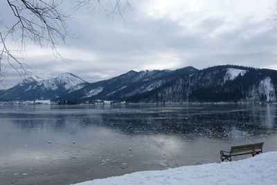 Scenic view of frozen lake by snowcapped mountains against sky