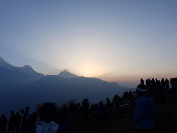 Tourists on mountain against sky during sunrise