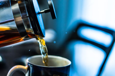 Close-up of coffee pouring from french press in cup