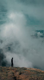 Rear view of man standing on mountain against sky