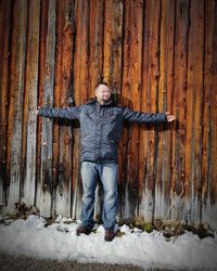 Portrait of smiling man standing by wooden fence