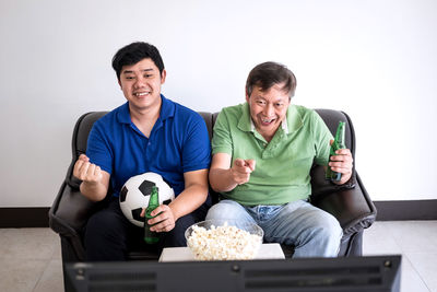 Family with food and drink watching sports on tv at home