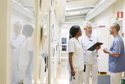 Smiling multi-ethnic doctors discussing while standing in hospital corridor