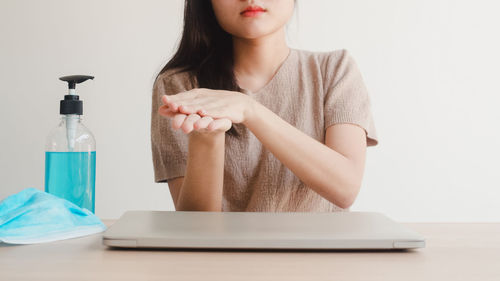 Close-up of woman looking at camera on table against wall