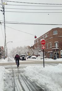 Rear view of man walking on snow covered field