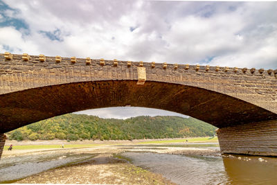 Low angle view of arch bridge over river against sky