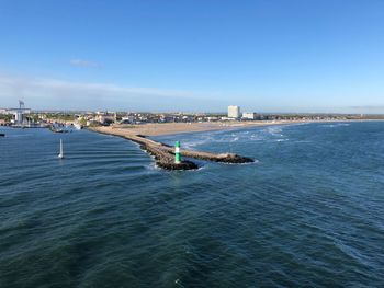 Scenic view of sea and buildings against blue sky