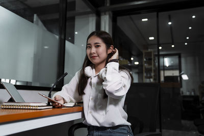 Portrait of young woman using phone at office