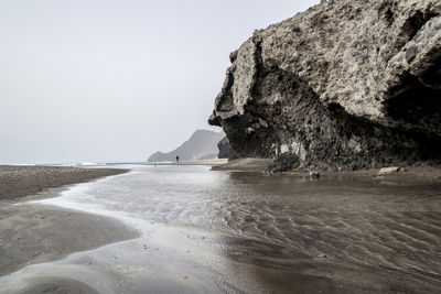 Rock formations on beach against clear sky