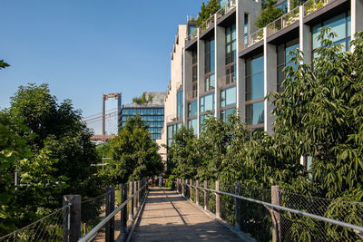 Footpath amidst trees and buildings against sky