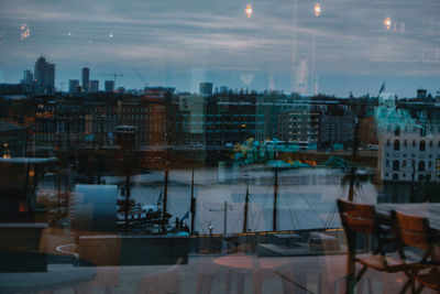 Sailboats in city against sky at dusk