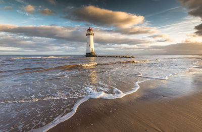 Lighthouse by sea against sky