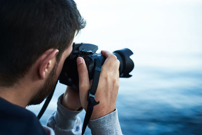 Portrait of man photographing against sea