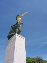 Low angle view of statue against blue sky