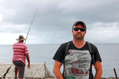 Portrait of man with friend standing at beach