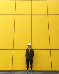 Full length of man standing against yellow wall