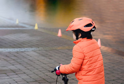 Side view of woman with bicycle standing on footpath