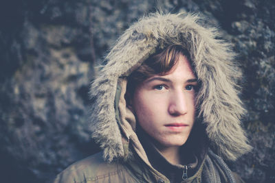 Close-up portrait of teenage boy in warm clothing standing outdoors