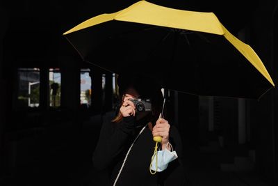 Portrait of woman with umbrella standing in the dark